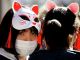 Японки в масках Манэки-нэко и защитных масках. Фото: Reuters
