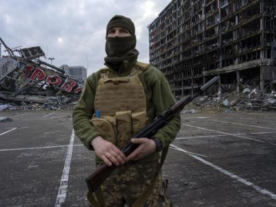 Украинский солдат на фоне разрушенного торгового центра в Киеве, 30 марта 2022 г. Фото: Rodrigo Abd / AP Photo
