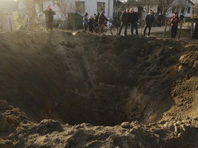 Люди смотрят на воронку от взрыва в селе Городня Черниговской области, Украина, 14 апреля 2022 года. Фото: George Ivanchenko / AP Photo